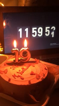 a birthday cake with lit candles sitting in front of a laptop