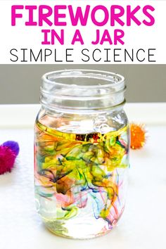 a jar filled with colorful flowers sitting on top of a white table next to a purple flower