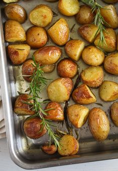 roasted potatoes with rosemary sprigs on a baking sheet