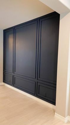 an empty room with black walls and wood floors