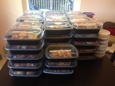 a stack of plastic containers filled with food sitting on top of a wooden table next to a window