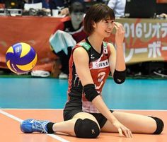 a woman sitting on the floor with a volleyball in her hand