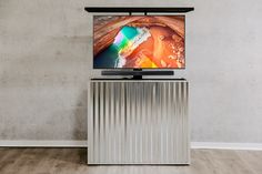 a flat screen tv sitting on top of a metal cabinet in front of a wall