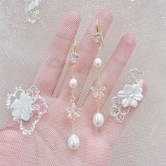 three pairs of pearl and crystal jewelry on a pink glove with white sequins