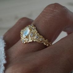 a close up of a person's hand wearing a ring with an oval stone