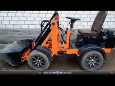 an orange and black tractor sitting next to a brick wall