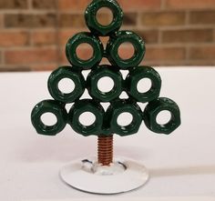 a christmas tree made out of green rings on top of a white table with a brick wall in the background