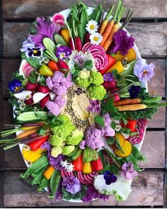 a platter filled with lots of different types of veggies on top of a wooden table