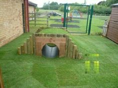 a dog house built into the grass in a back yard