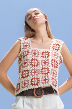 a woman wearing a red and white crochet top with her hands on her hips