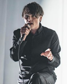 a man sitting on top of a chair while holding a microphone in his right hand