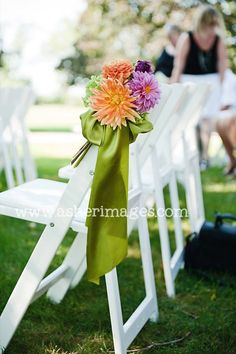 an orange and pink flower is tied to a white lawn chair with green ribbon on it