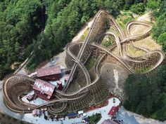 an aerial view of a roller coaster in the middle of a wooded area with trees surrounding it