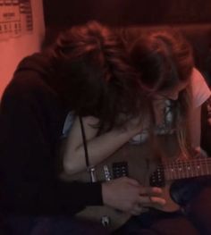 two people sitting on a couch playing guitar