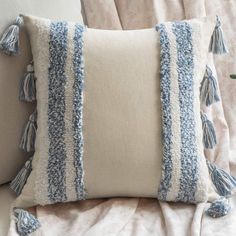 a blue and white pillow with tassels on it