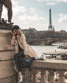 a woman leaning against a wall next to a statue