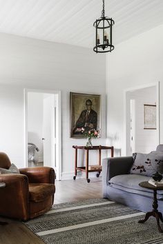 a living room filled with furniture and a painting hanging on the wall above it's doorway