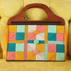 a colorful purse sitting on top of a yellow chair next to a wooden buttonhole