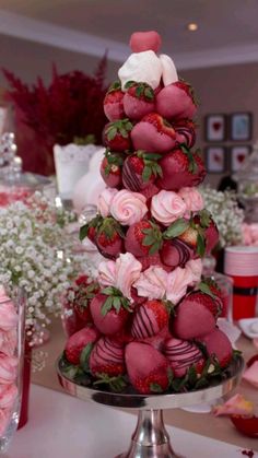 a cake made to look like strawberries with roses and hearts on the top tier