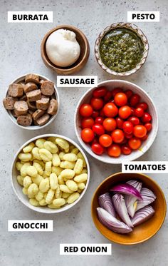 different types of food are shown in bowls on the table, including tomatoes, onions, and sausage