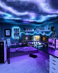 a computer desk with two monitors and speakers under a cloudy sky filled with clouds in a bedroom