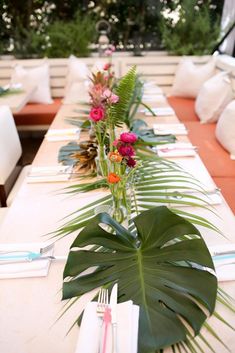 a long table is set with flowers and place settings for an outdoor dinner or party