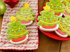 decorated christmas cookies sitting on top of a red plate next to a green ornament