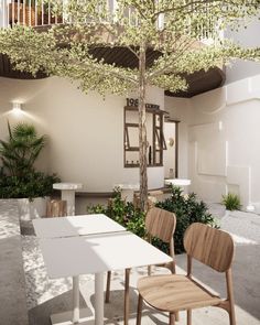 a table and chairs under a tree in a room with stairs to the second floor