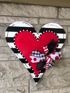 a heart shaped door hanger on the side of a brick wall with black and white stripes