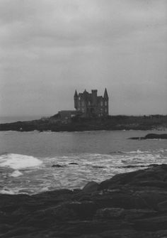 an old castle sits on top of a rock outcropping next to the ocean