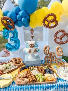 a blue and white table topped with lots of food next to balloon shaped archetys