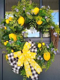 a wreath with lemons and blue flowers hanging on the front door, decorated with gingham ribbon