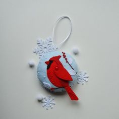 a red bird ornament hanging on a white background with snowflakes around it