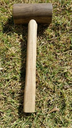 an old wooden baseball bat laying on the ground next to a mallet in the grass