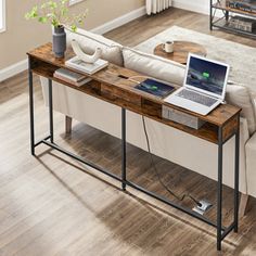 a laptop computer sitting on top of a wooden table next to a white couch in a living room