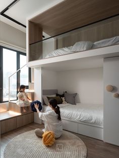 a woman sitting on top of a bed next to a child in a room with bunk beds