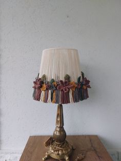 a lamp that is sitting on top of a wooden table next to a white wall