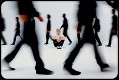 a woman sitting on the ground in front of a group of people with their legs crossed