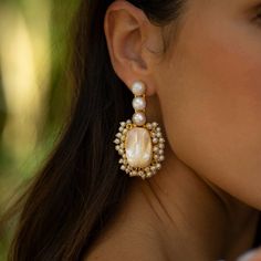 a close up of a person wearing some kind of earring with pearls on it