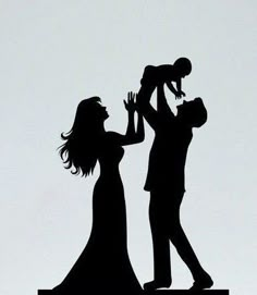 a silhouette of a man and woman holding a baby up in the air with their hands