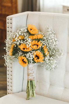 a bouquet of sunflowers and baby's breath sits on a white chair