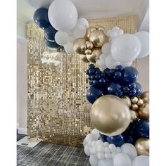 balloons are hanging from the ceiling in front of a gold and blue wall with sequins