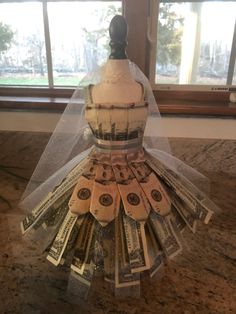 a mannequin made out of dollar bills on top of a counter with a veil over it