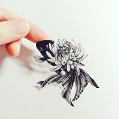 a hand holding a piece of paper with an image of a fish and flowers on it