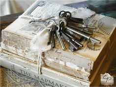 a bunch of keys are on top of an old book that is covered in lace