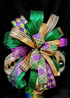 a green, purple and gold bow on top of a black cloth covered tablecloth