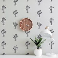 a clock is on the wall next to a potted plant in front of it