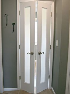 two white doors are open in the corner of a room with gray walls and tan carpet