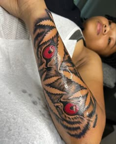 a man with a tattoo on his arm has red eyes in the shape of a tiger's head