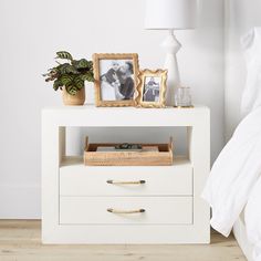 a white night stand with two photos on it